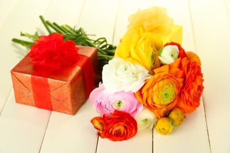 Ranunculus (persian buttercups) and gifts, on white wooden backgroundの写真素材