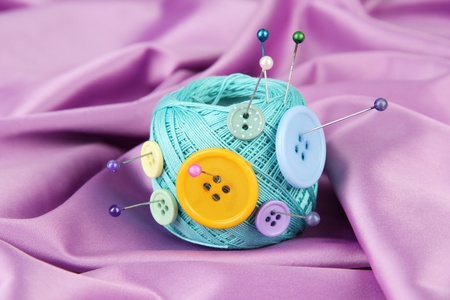 Colorful buttons and wool ball, on color fabric background