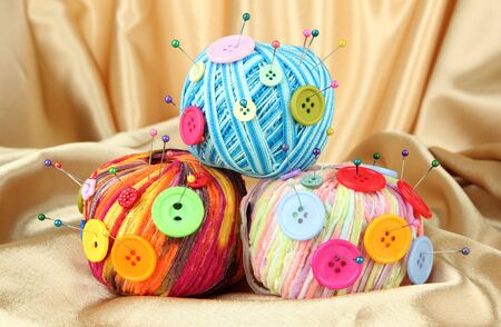 Colorful buttons and multicolor wool balls, on color fabric backgroundの写真素材