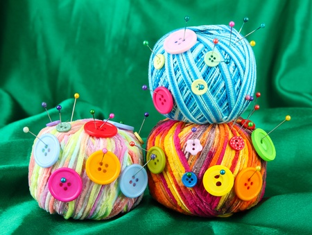 Colorful buttons and multicolor wool balls, on color fabric background