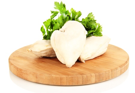Boiled chicken breast on wooden cutting board with parsley isolated on whiteの写真素材