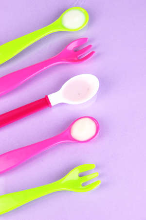 Color spoons and forks for baby food on purple backgroundの写真素材