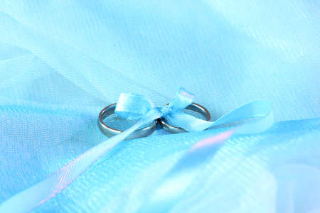 Wedding rings tied with ribbon on cloth backgroundの写真素材