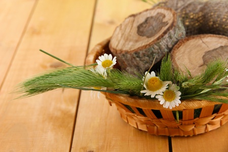 Many spikelets and chamomile on satin in basket on wooden backgroundの写真素材