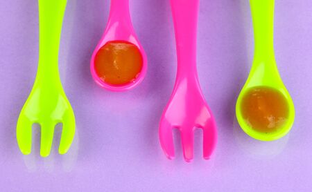 Color spoons and forks for baby food on purple backgroundの写真素材