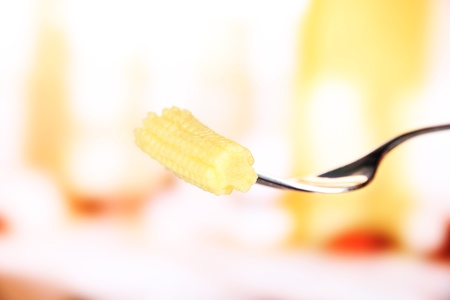 Baby corn sticking on fork, on bright backgroundの写真素材