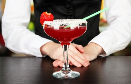 Barmen hand with shaker  pouring cocktail into glass, on close upの写真素材