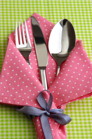 Fork spoon and knife in napkin on fabric checkered backgroundの写真素材