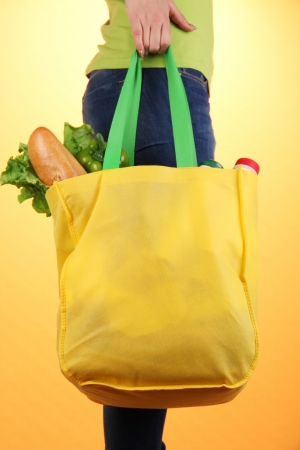 Girl with shopping bag on orange backgroundの写真素材
