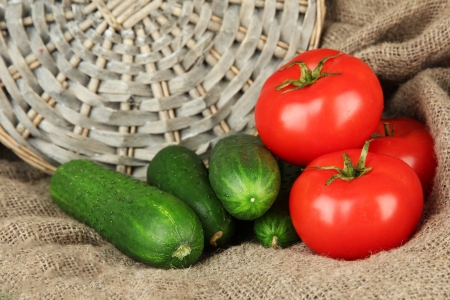 Tasty green cucumbers and red tomatoes on sackcloth backgroundの写真素材