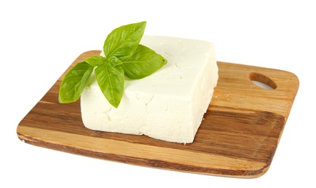 Sheep milk cheese with basil on cutting board, isolated on whiteの写真素材