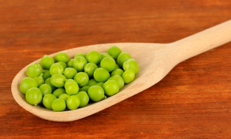 Sweet green peas in spoon on wooden backgroundの写真素材