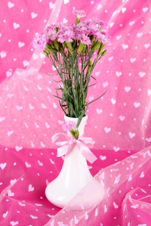 Many small pink cloves IN vase on light pink fabric backgroundの写真素材