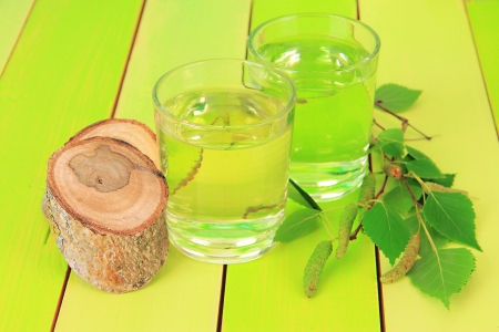Glasses of birch sap on green wooden tableの写真素材