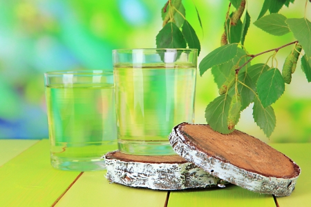 Glasses of birch sap on wooden table, on green backgroundの写真素材