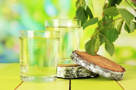 Glasses of birch sap on wooden table, on green backgroundの写真素材