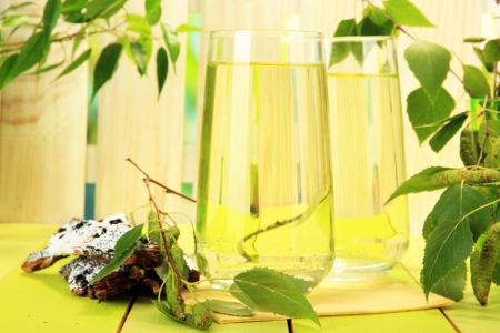 Glasses of birch sap on green wooden tableの写真素材
