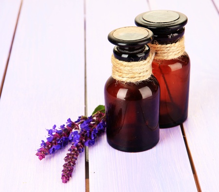 Medicine bottles and salvia flowers on purple wooden backgroundの写真素材