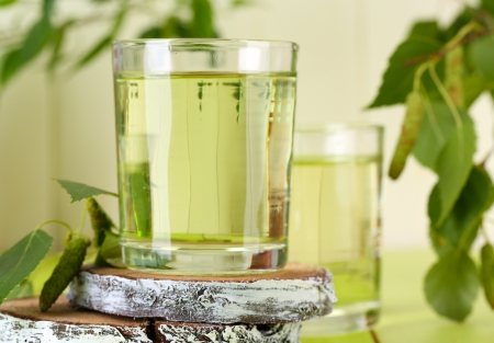 Glasses of birch sap on green wooden tableの写真素材