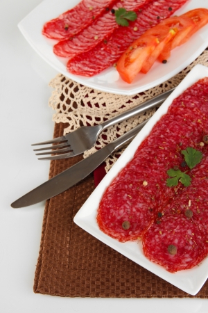Tasty salami on plates on  napkin isolated on whiteの写真素材