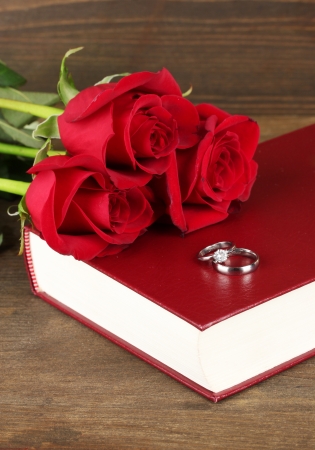 Wedding rings on bible with roses on wooden backgroundの写真素材