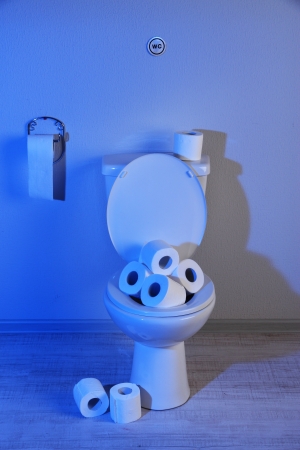 Toilet bowl and toilet paper in a bathroom with blue lightの写真素材