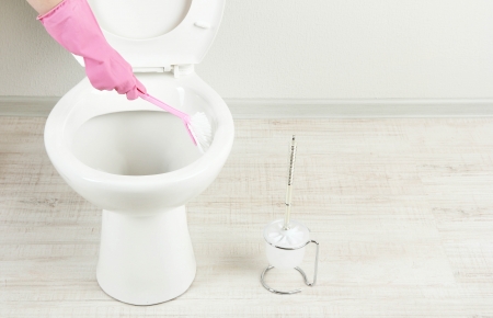 Woman hand with brush cleaning a toilet bowl in a bathroomの写真素材