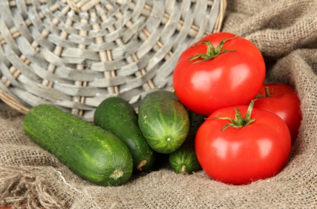 Tasty green cucumbers and red tomatoes on sackcloth backgroundの写真素材