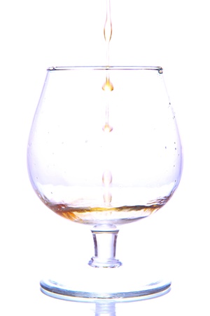 Brandy pouring into glass isolated on whiteの写真素材