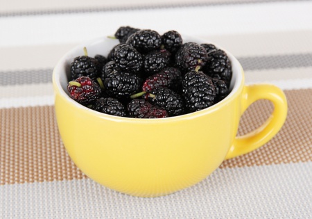 Ripe mulberries in cup on table in roomの写真素材