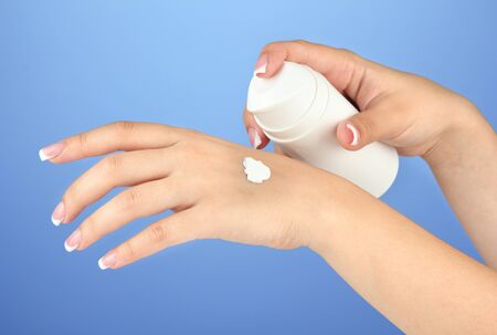 Woman applying cream on hands on color backgroundの写真素材