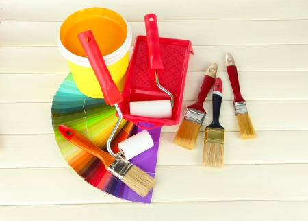 Set for painting: paint pot, brushes, paint-roller on white wooden tableの写真素材