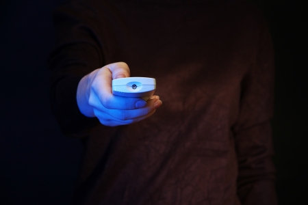 Woman hand holding a TV remote control, on dark backgroundの写真素材