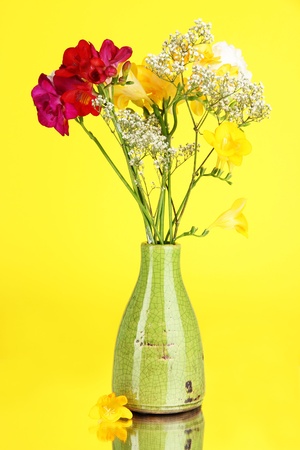Beautiful bouquet of freesia in vase on yellow backgroundの写真素材