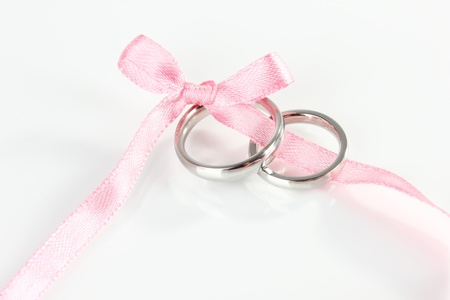 Wedding rings tied with ribbon isolated on whiteの写真素材