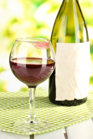 Glass of wine and bottle on table on nature backgroundの写真素材