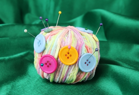 Colorful buttons and multicolor wool ball, on color fabric background