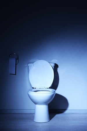 Toilet bowl in a bathroom with blue lightの写真素材