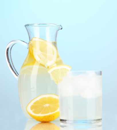 Lemonade in pitcher and glass on blue backgroundの写真素材