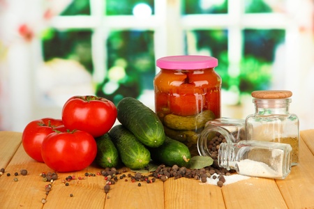 Tasty  fresh and canned cucumbers and red tomatoes, on wooden table on bright  backgroundの写真素材
