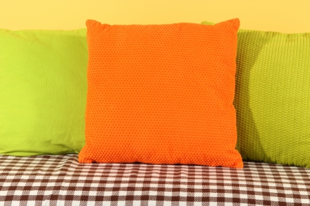 Colorful pillows on couch on yellow backgroundの写真素材