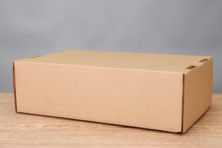 Parcel box on wooden table, on grey background