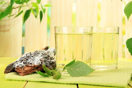 Glasses of birch sap on green wooden tableの写真素材