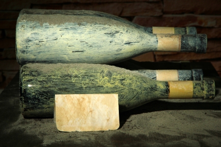 Old bottles of wine in old cellar, on dark  backgroundの写真素材