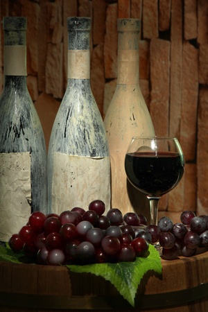 Composition with old bottles of wine and wineglass in old cellarの写真素材