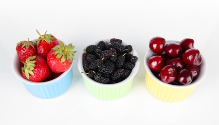Ripe mulberries with cherry and strawberries in bowls isolated on white