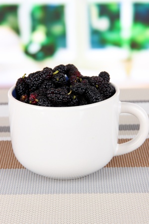 Ripe mulberries in cup on table in roomの写真素材