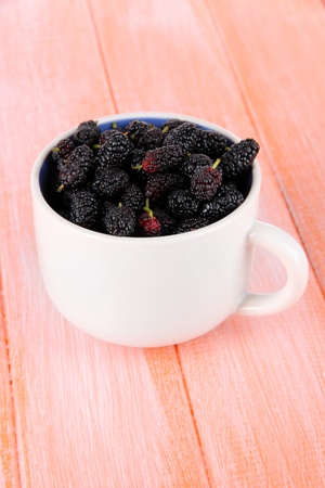 Ripe mulberries in cup on wooden backgroundの写真素材