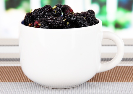 Ripe mulberries in cup on table in roomの写真素材