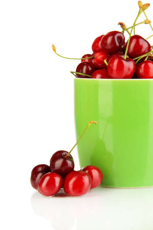 Ripe red cherry berries in cup isolated on whiteの写真素材